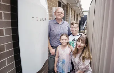 A family standing beside their home battery